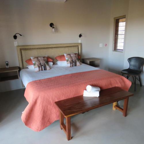 a bedroom with a bed with a red blanket and a table at Kanaan, Mabalingwe in Mabula