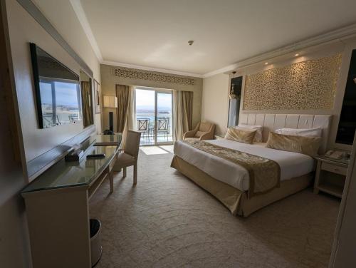 a hotel room with a large bed and a desk at KaiSol Romance Resort Sahl Hasheesh - Adults Only in Hurghada