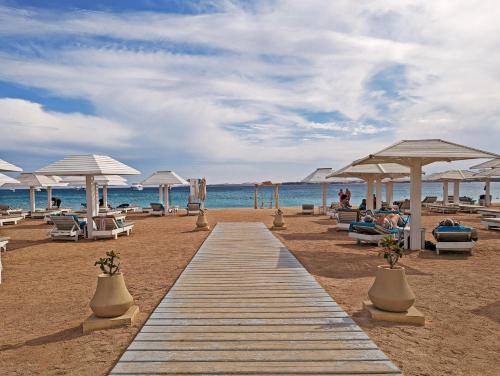 een promenade op een strand met stoelen en parasols bij KaiSol Romance Resort Sahl Hasheesh - Adults Only in Hurghada