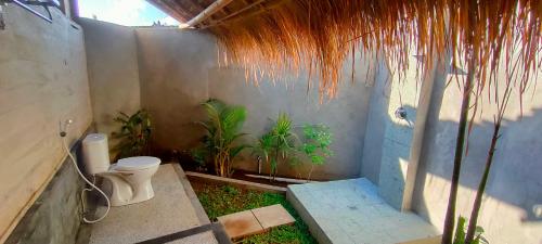 bagno con servizi igienici e alcune piante di Yogi Beach Cabin ad Amed