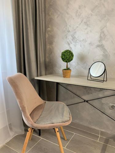 une chaise assise à côté d'un bureau avec un miroir dans l'établissement Chic Galati Apartment: Urban Escape, à Galaţi