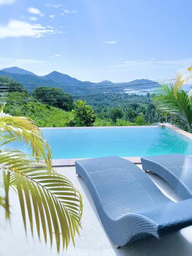 a swimming pool with two chairs and a palm tree at Mantra Sea View Villa in Chaloklum
