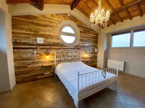 ein Schlafzimmer mit einer Wand mit Holzakzenten und einem Bett mit einem Kronleuchter in der Unterkunft Casa Fevira Borgo in Borgo San Lorenzo