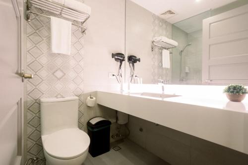 bagno bianco con servizi igienici e lavandino di Allure Hotel & Suites a Cebu City
