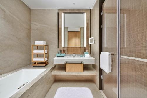 a bathroom with a tub and a sink and a mirror at Hilton Suzhou Wuzhong in Suzhou