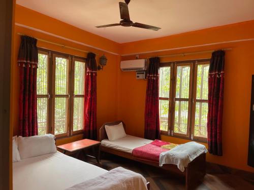 a bedroom with two beds and a ceiling fan at Tara guesthouse - Sauraha,Chitwan in Sauraha