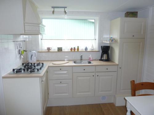 a white kitchen with a sink and a window at B&B It Lytshûs in Earnewâld