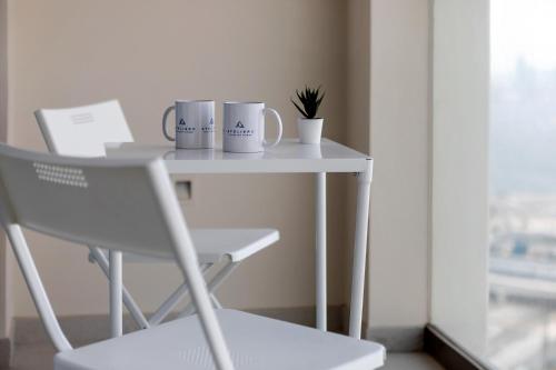 a table with two mugs and a chair next to a window at Luxury apartments at Vida Residences in Dubai
