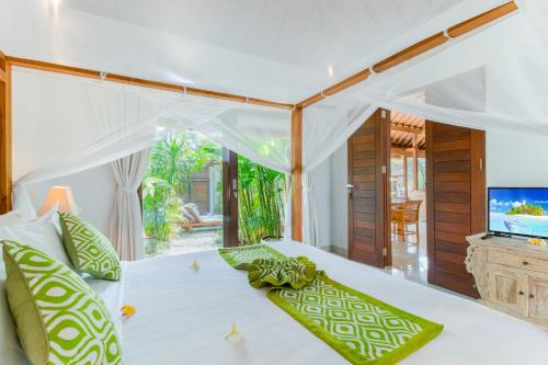 a bedroom with a bed with green pillows and a television at Villa Istana 1 in Seminyak