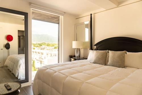 a bedroom with a large white bed with a large window at Sunset Paradise Residence in Puerto Vallarta