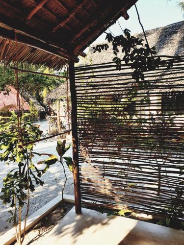 a window with blinds on it with a plant at Michamvi Spirit Lodge in Michamvi