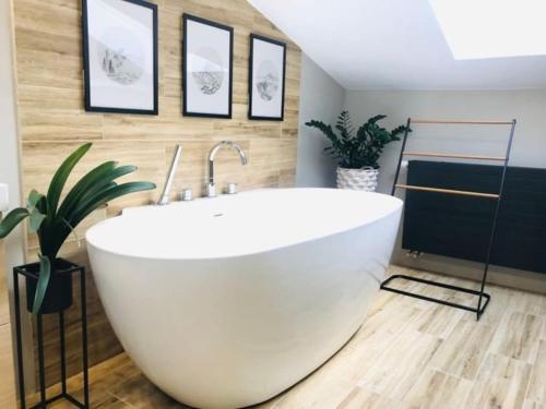 a white bath tub in a bathroom with pictures on the wall at Qwadrat Apartament 15 in Bielsko-Biala city center in Bielsko-Biala