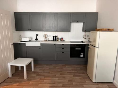 a kitchen with black cabinets and a white refrigerator at 73 George Street. Appartment 1 in Oban