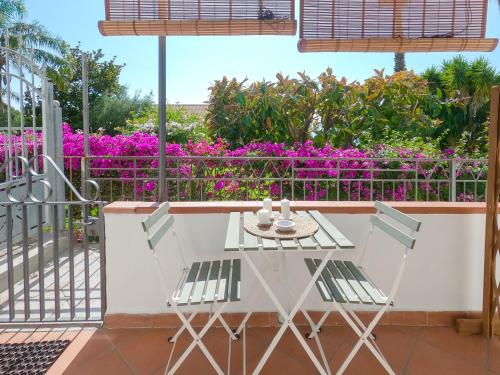 einen Tisch und Stühle auf einem Balkon mit lila Blumen in der Unterkunft A 50 scalini dal mare - Camera Doppia Privata in Maratea