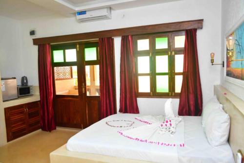 a bedroom with a white bed with red curtains at Kahawa Sunset View Zanzibar in Zanzibar City