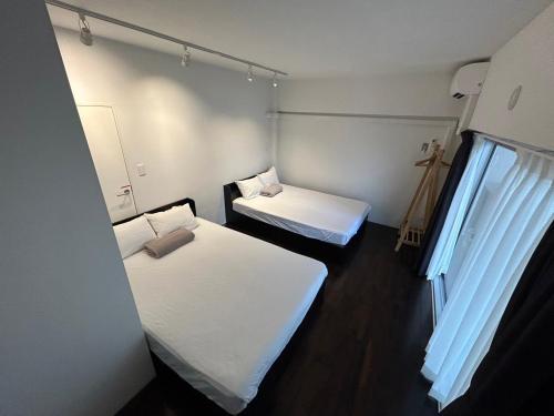 東京にあるNIYS apartments 74 typeのベッド2台と窓が備わる小さな客室です。