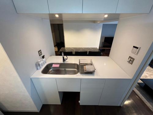 a white kitchen with a sink and a mirror at NIYS apartments 74 type in Tokyo