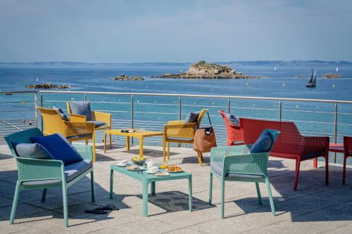 a group of chairs and tables on a balcony with the ocean at Hôtel la Baie Valdys Resort & SPA in Douarnenez