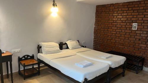two beds in a room with a brick wall at La Petite Guest House in Bogmolo