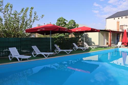 een zwembad met 2 stoelen en parasols naast een zwembad bij Hotel West Face in Koetaisi