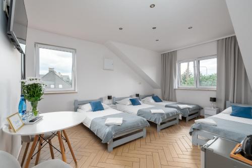 Pokój z 4 łóżkami, stołem i oknami w obiekcie Sleeply Pensjonat Złotniki we Wrocławiu