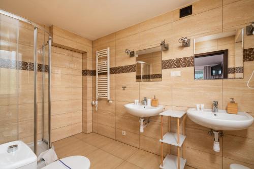 a bathroom with two sinks and a shower at Sleeply Pensjonat Złotniki in Wrocław