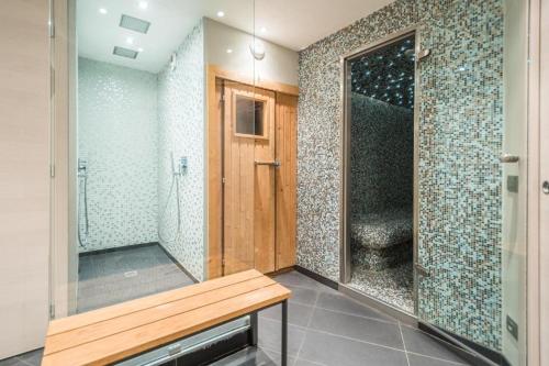 een badkamer met een douche en een houten bank bij Résidence Le Portillo in Val Thorens