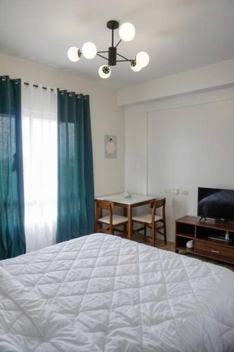 een slaapkamer met een bed, een tafel en een raam bij Studio condo for rent in Bacolod