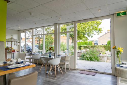 een eetkamer met een tafel en stoelen en glazen schuifdeuren bij Hotel Kijkduin in Domburg