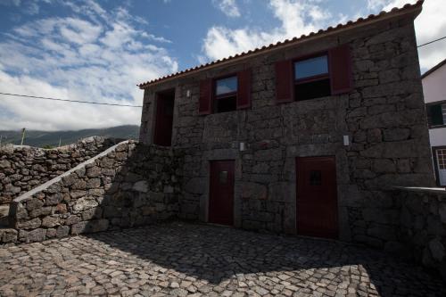 a stone house with red doors and a stone wall at Pico da Saudade in Prainha de Baixo