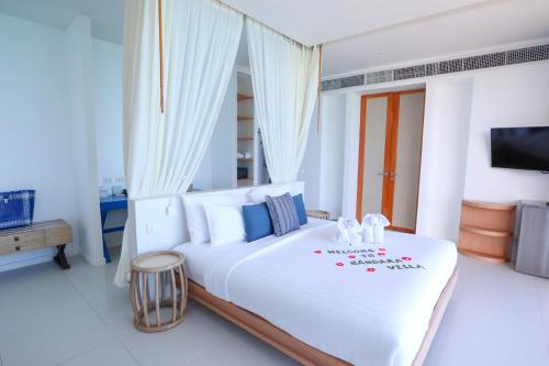 a bedroom with a large white bed with a tv at Bandara Pool Villas, Phuket in Panwa Beach