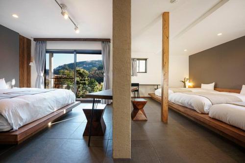 a bedroom with two beds and a large window at VILLA ATAMI -Nagomi- in Atami
