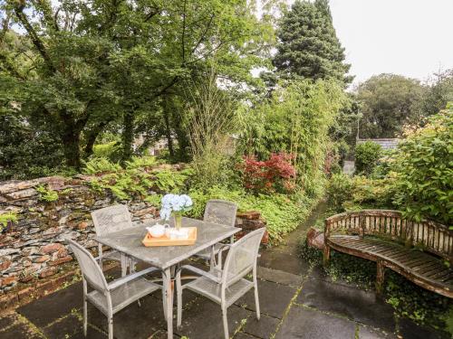 a patio with a table and chairs and a bench at Ty Nain in Caernarfon