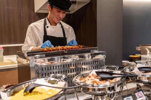 a chef preparing food in a restaurant kitchen at Relax Hotel Takayama Station in Takayama