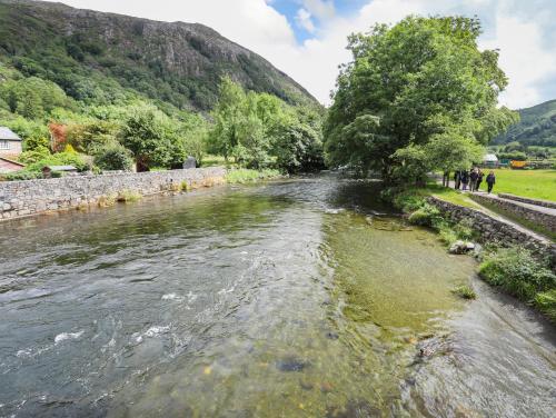 a river in the mountains with people walking along it at Ty Nain in Caernarfon