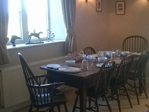 uma mesa de jantar com cadeiras, uma mesa e uma mesa; em Battens Farm Cottages B&B em Yatton Keynell