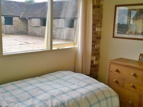1 dormitorio con ventana, 1 cama y vestidor en Battens Farm Cottages B&B en Yatton Keynell