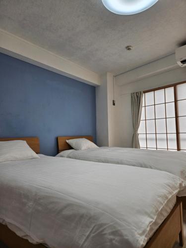 two beds in a bedroom with a blue wall at STAY ARI Kabukicho in Tokyo