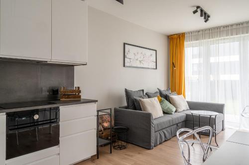 a living room with a couch and a kitchen at RentPlanet - Port Popowice in Wrocław