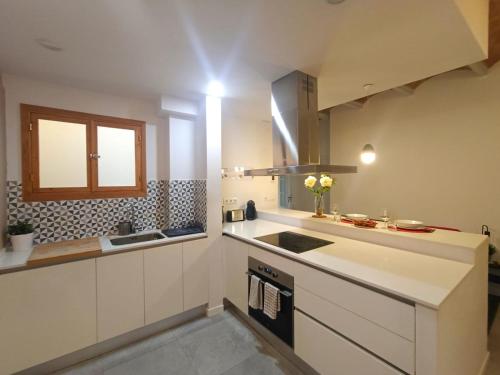 eine Küche mit weißen Schränken, einem Waschbecken und einem Fenster in der Unterkunft Private rooms in Gothic in Barcelona