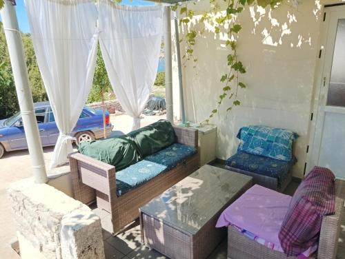 eine Veranda mit Stühlen, einem Sofa und einem Tisch in der Unterkunft CAPTAIN'S Holiday HOUSE in Žirje