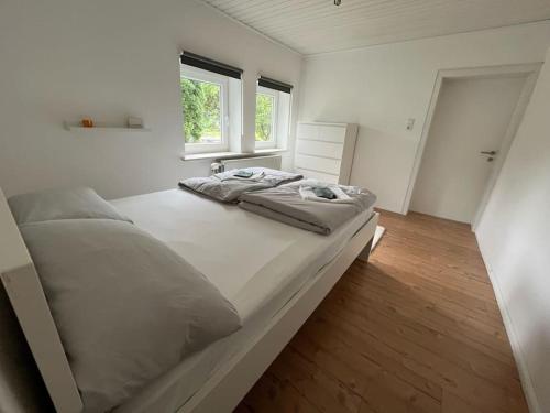 a large white bed in a room with two windows at Altes Bauernhaus in der Natur in Detmold