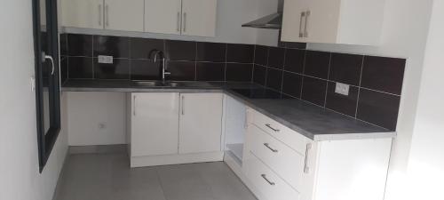 une cuisine avec des armoires blanches et un évier dans l'établissement KATHY, à Montpellier