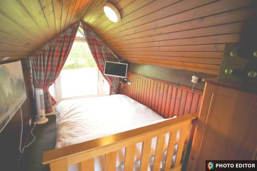a bedroom with a bed in a room with a window at Iona Cabin in Taynuilt