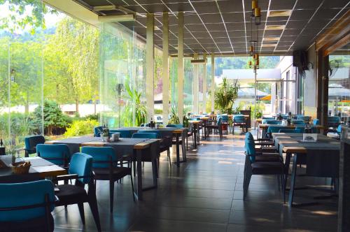 a restaurant with tables and blue chairs and windows at Hemus Hotel - Vratza in Vratsa