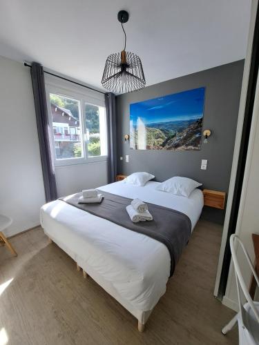 a large bed in a room with a large window at Hôtel Les Mouflons in Le Mont-Dore