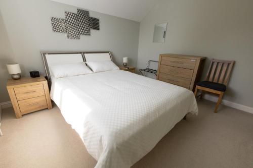 um quarto com uma grande cama branca e uma cadeira em Orchard View B&B em Whitminster