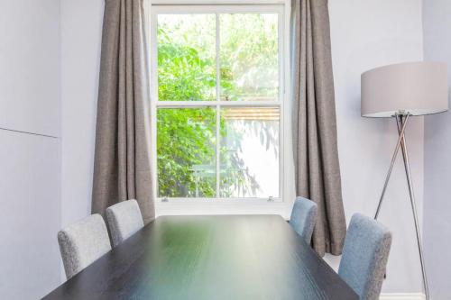 a dining room table with chairs and a window at Modern and Stylish 2 Bedroom House in Brighton in Brighton & Hove
