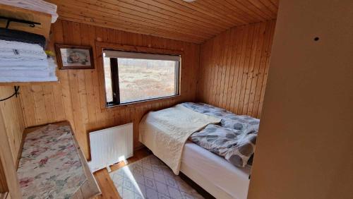 a small bedroom with a bed in a wooden cabin at Thingvellir Lake Cottage in Veiðilundur