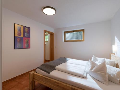 a white bedroom with a bed and a window at Appartements Wanner in Gerlos